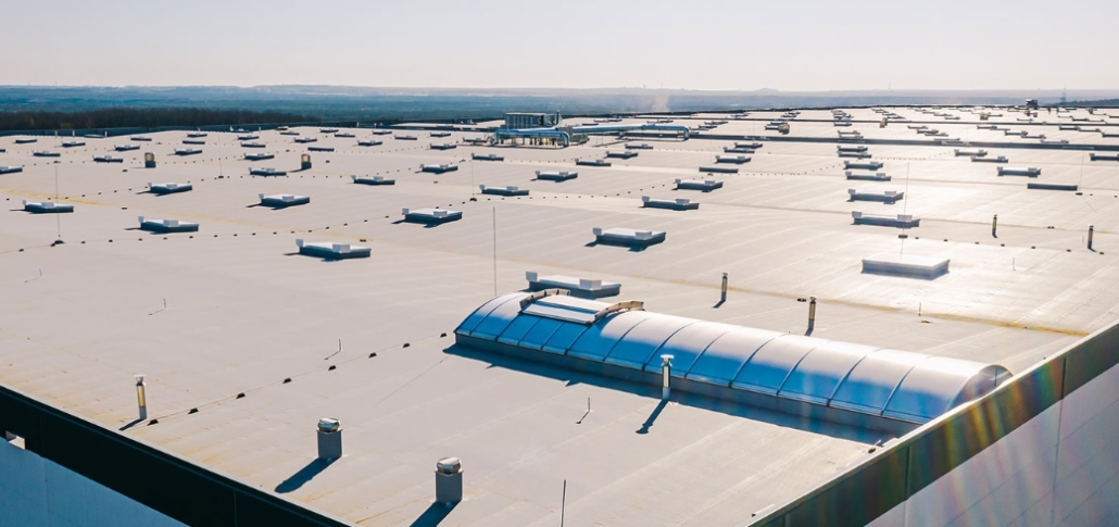 A wide view of a commercial structure with white roofs, highlighting key factors in roof replacement costs.