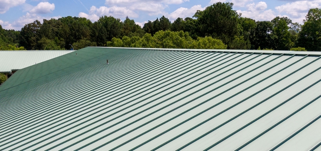 A green roof featuring a metal roofing system, illustrating a commercial roof replacement project focused on cost efficiency.