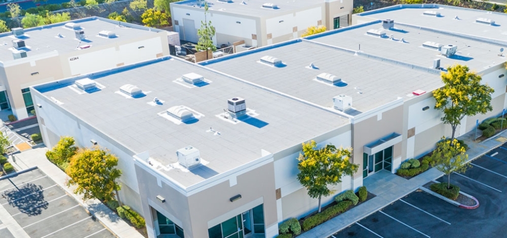 Aerial view of a commercial building featuring a flat roof and adjacent parking lots, highlighting single-ply roofing systems.