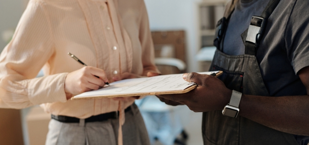 A man and woman stand next to a clipboard, focusing on warranty and documentation for the commercial roof replacement process.