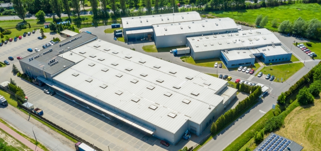 Aerial view of a large industrial building, showcasing its roof and surrounding area, relevant to commercial roofing materials.
