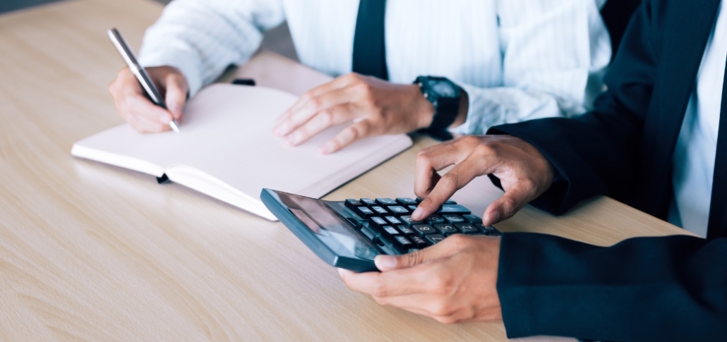 Two business professionals calculate costs and ROI for commercial roofing materials.