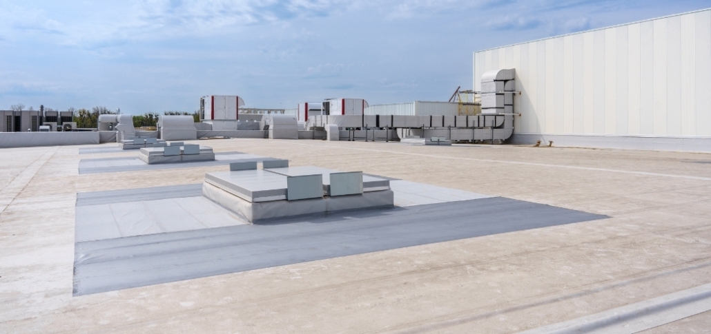 An expansive industrial structure with a concrete floor and a flat roof, highlighting roofing material options.