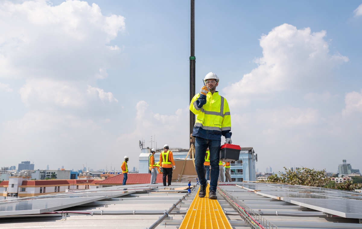 A man wearing a yellow safety vest stands on a rooftop, symbolizing the work of an Industrial Roofing Company.