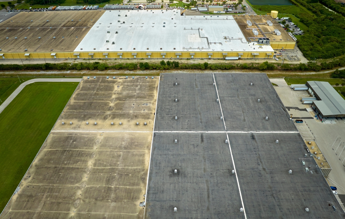 Aerial view of a commercial office building with a parking lot, highlighting the roof for potential repair work.
