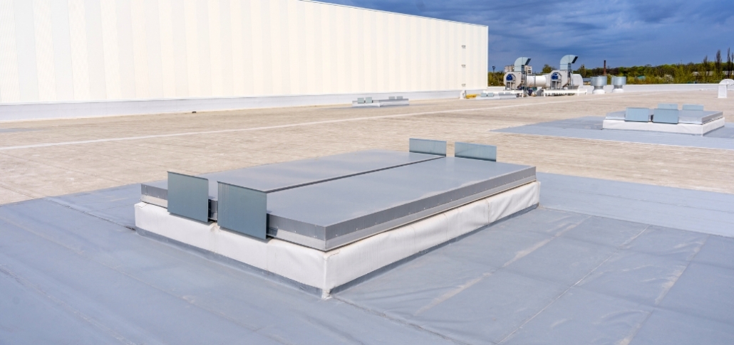 A large flat roof with a metal box on top, illustrating the layout for TPO membrane installation.