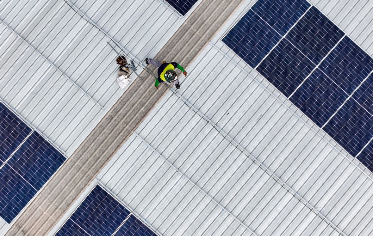 Aerial perspective of two people on a warehouse roof, highlighting their position and the surrounding rooftop area.