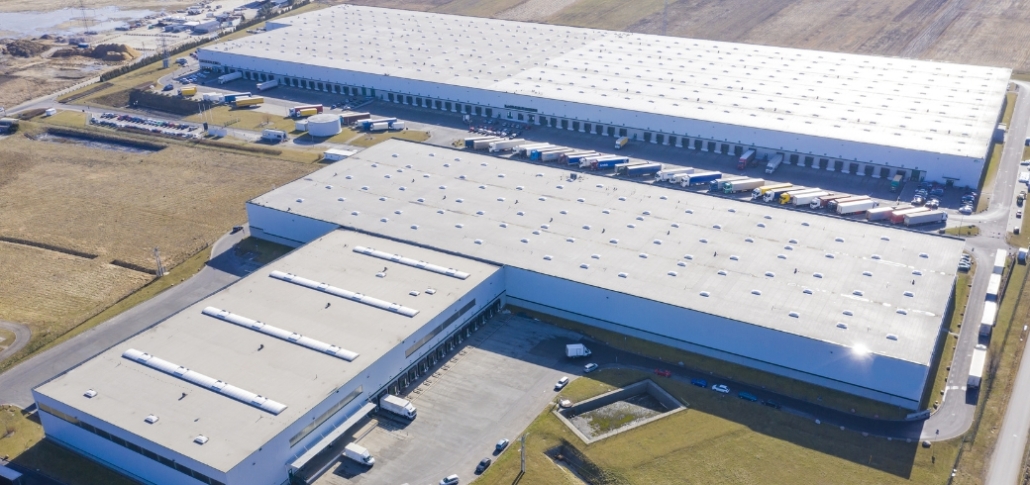 Aerial view of a large warehouse surrounded by numerous trucks, illustrating potential for solar panel installation.