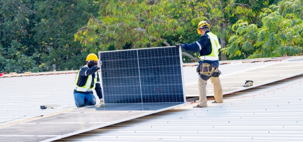 Two men on a rooftop, working on a solar panel installation, focusing on commercial solar panel suitability.