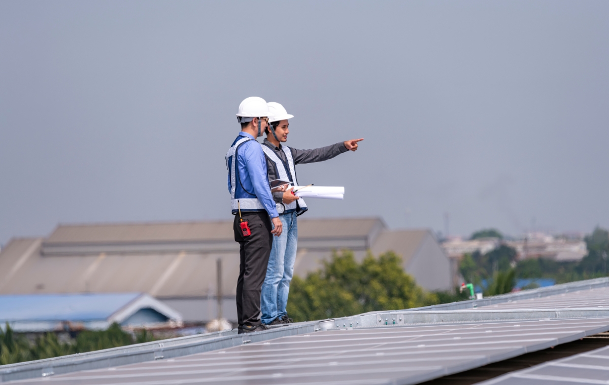 Two men on a rooftop, focused on inspection for a commercial roofing project in Connecticut.