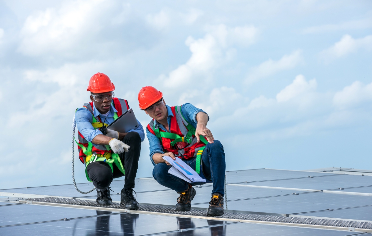 Two men in hard hats and safety vests on a rooftop, illustrating commercial roof services in Stratford, CT.