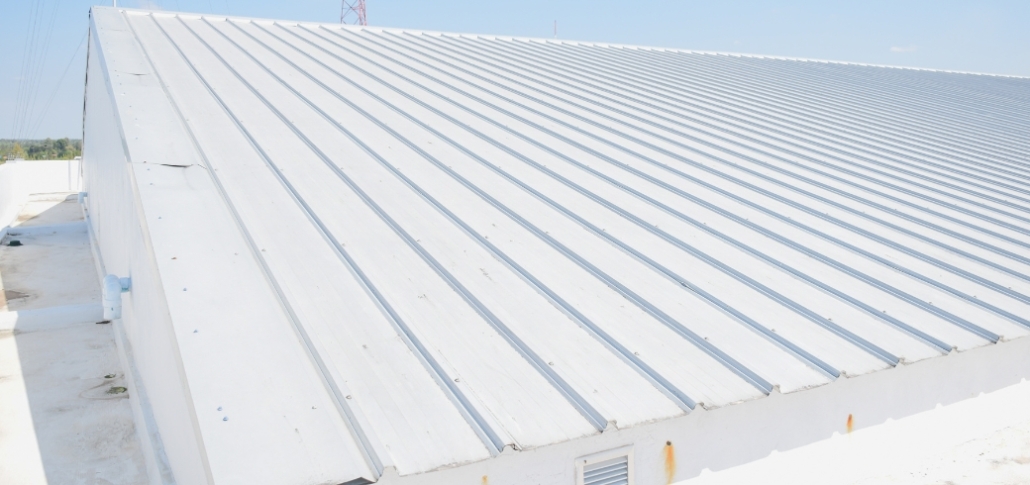 Expansive white metal roof on a manufacturing facility, highlighting robust roofing solutions for industrial applications.