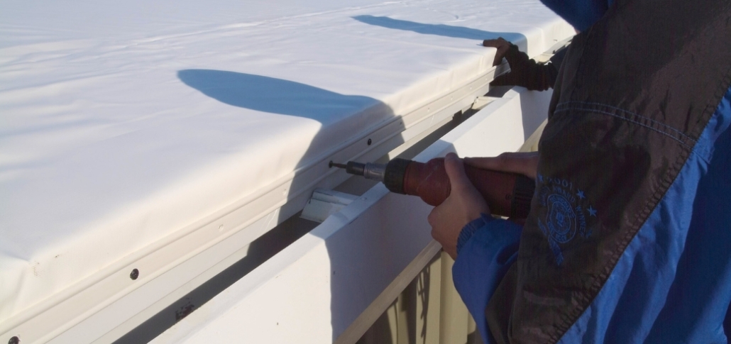A worker operates a drill for EPDM roof installation, concentrating on drainage execution and quality control measures.
