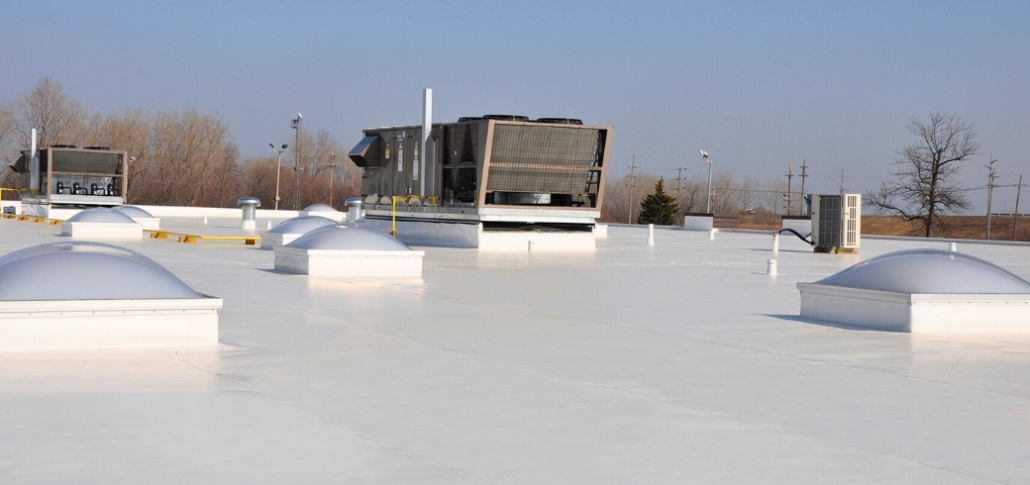 A flat roof displaying various air conditioning units, alongside materials organized for EPDM roof installation during a weather window.